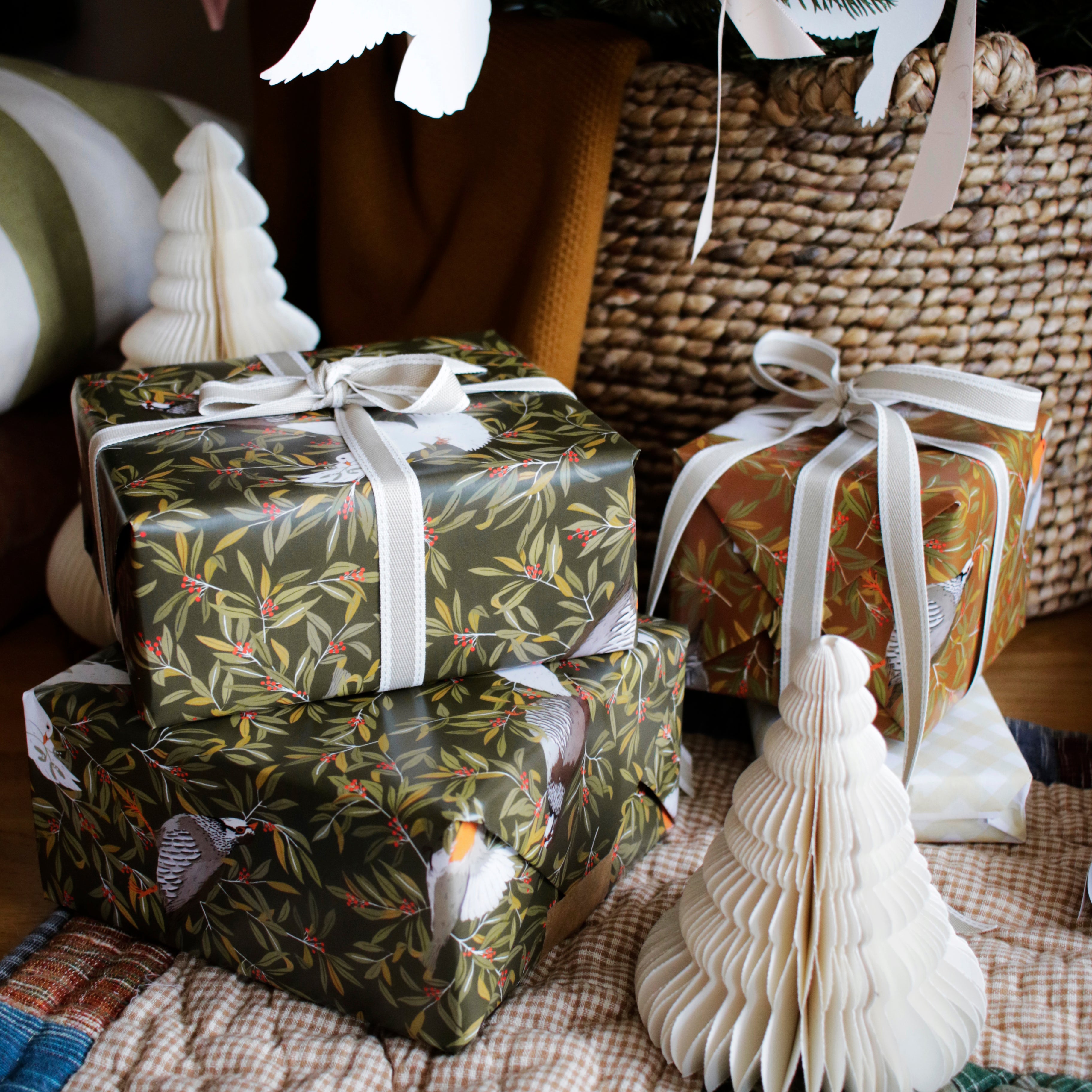 wrapped gifts in illustrated bird christmas wrapping paper under the tree