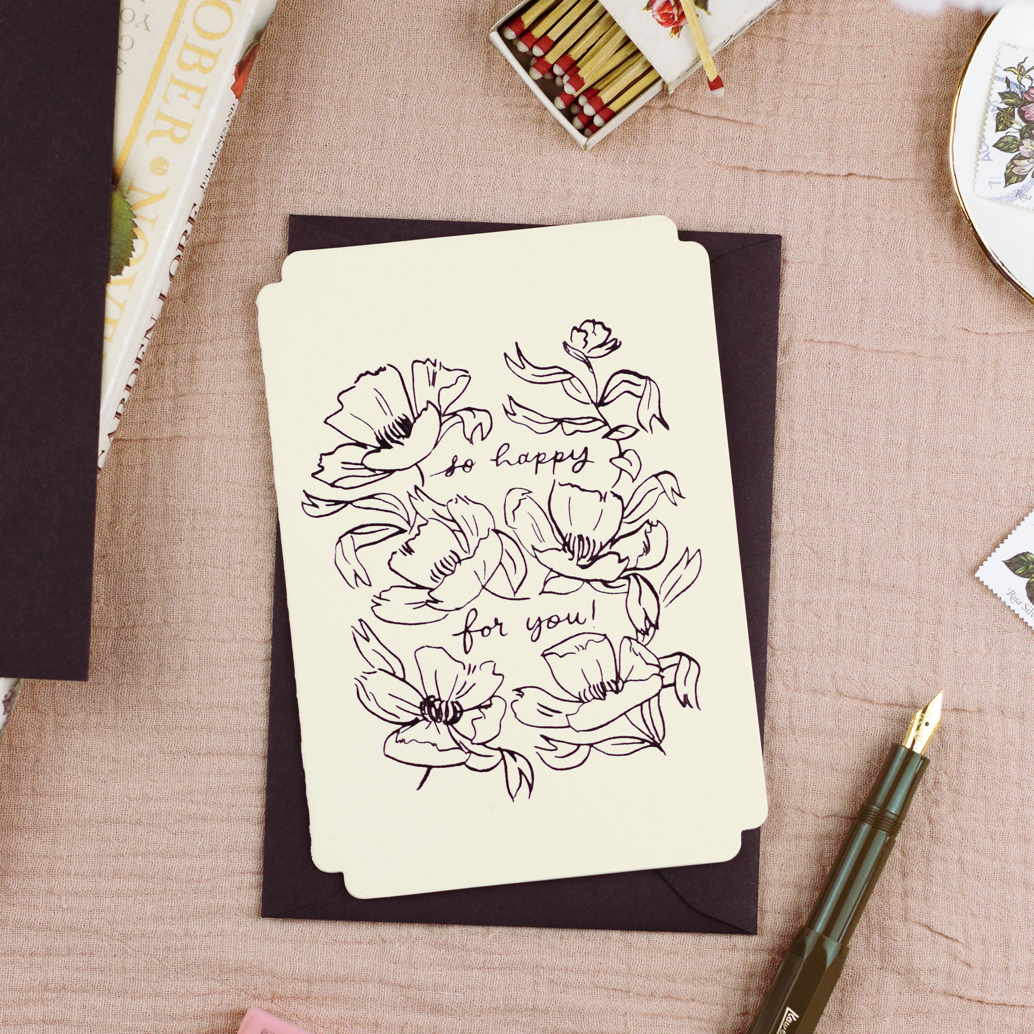 A congratulations card with embossed, black foil, floral design reads "so happy for you!" - Annie Dornan Smith