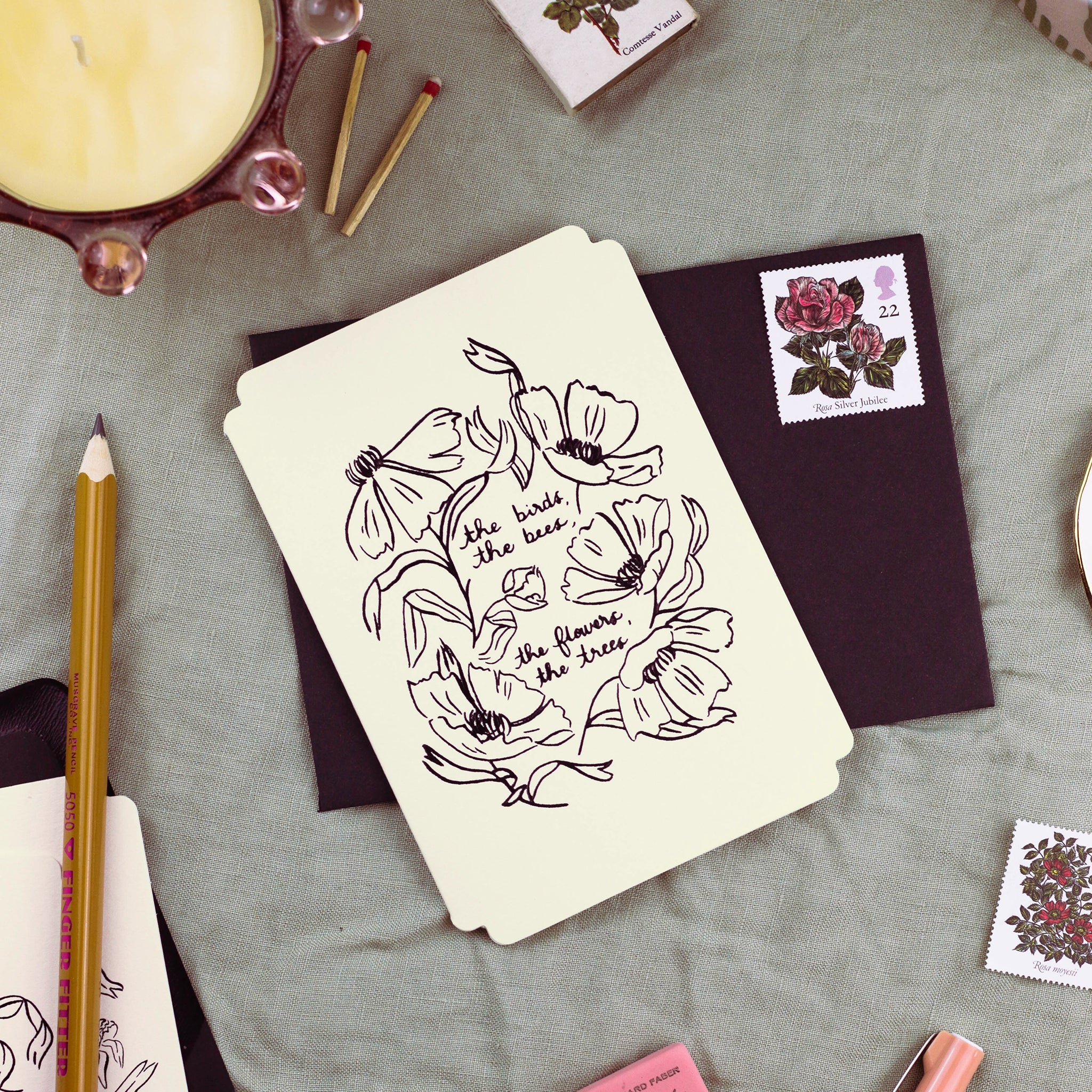 A just because card in a soft cream colour, cut in a vintage postcard style shape, reads "the birds, the bees, the flowers, the trees" in black foil, surrounded by black foiled linework-style flowers.  Comes with a black envelope.