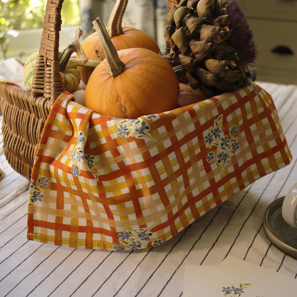 the gingham and floral patterned teatowel used to decorate a gift basket of pumpkins and dried flowers