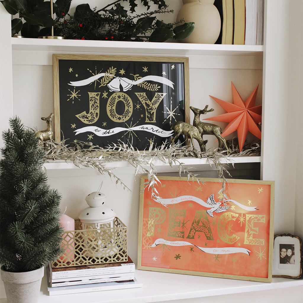 Navy Christmas Print With Gold Joy Lettering And Stars In An Oak Frame On A Book Shelf - Annie Dornan Smith