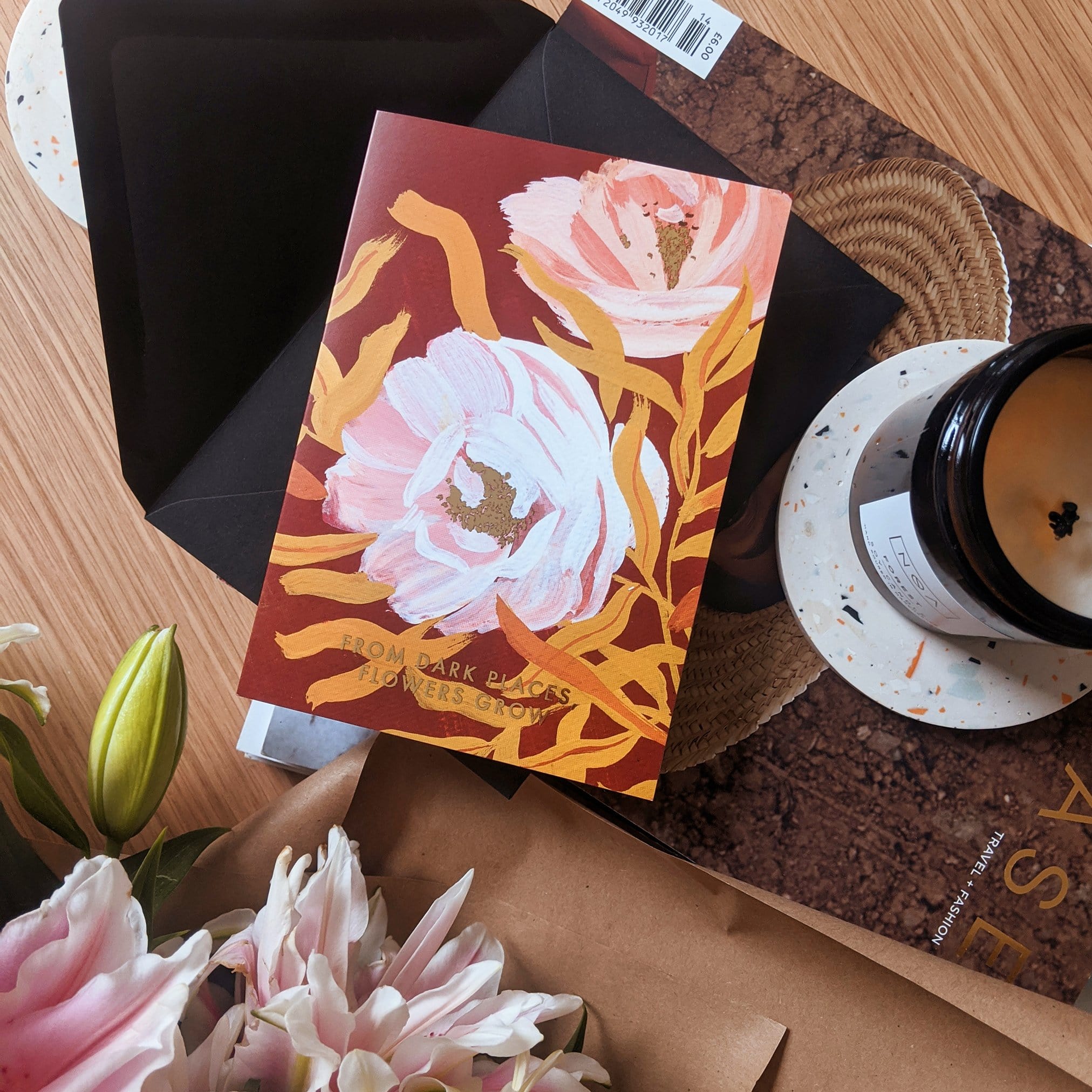 Botanical Greeting Card Pink English Tea Roses On Warm Brown Background With The Words From Dark Places Flowers Grow In Gold With Black Envelope Next To A Candle - Annie Dornan Smith