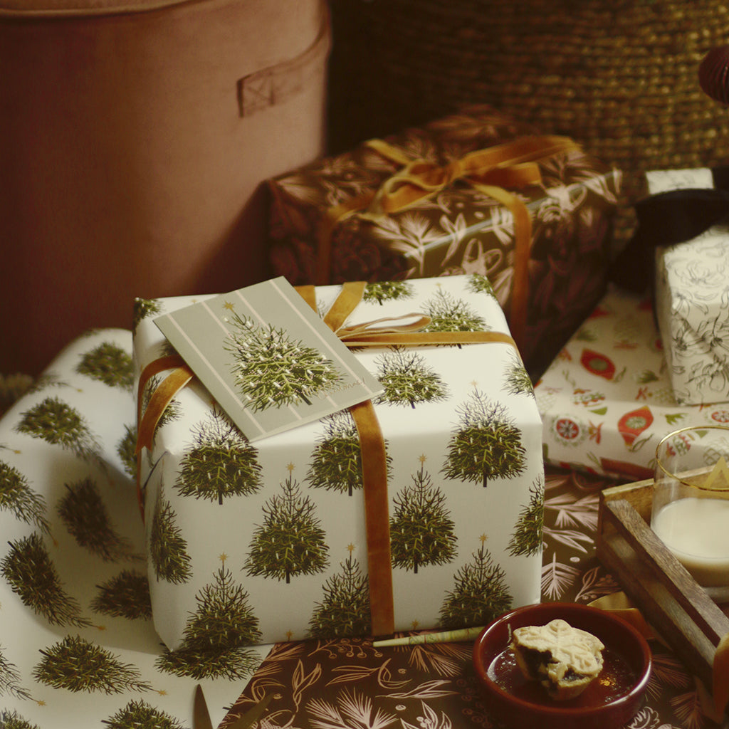 wrapping gifts by the tree, using christmas tree patterned wrapping paper