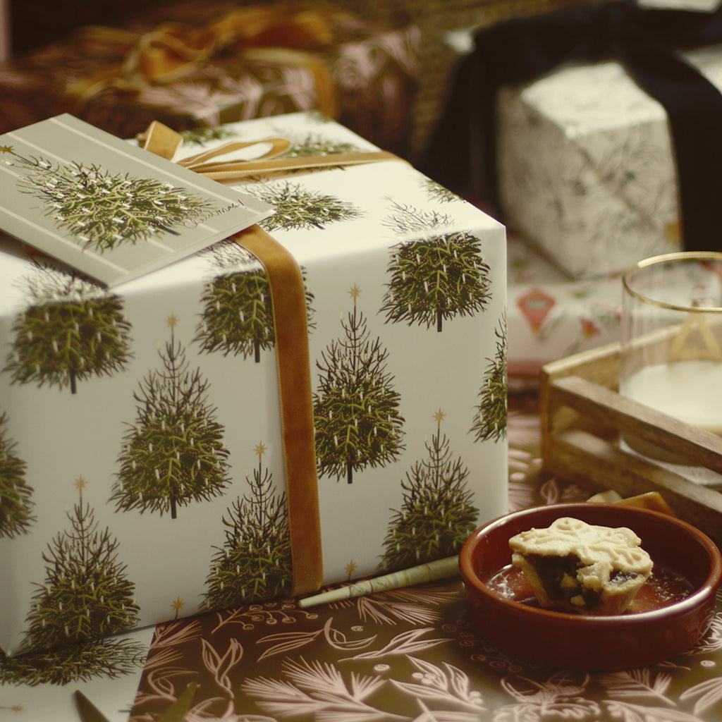 illustrated christmas tree pattered wrappingp pape tied with gold velvet ribbonr