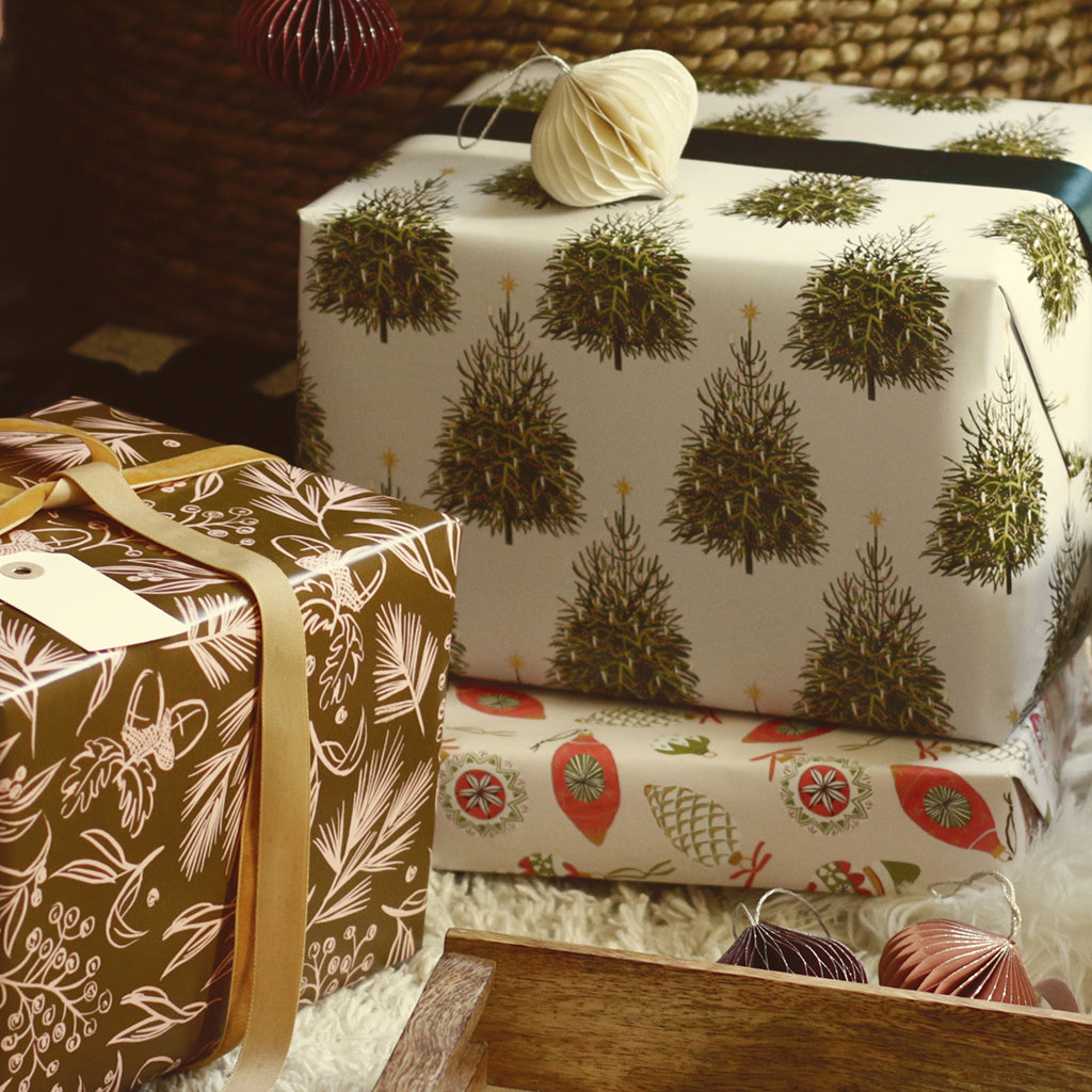 a pile of gifts in illustrated wrapping paper, below the christmas tree