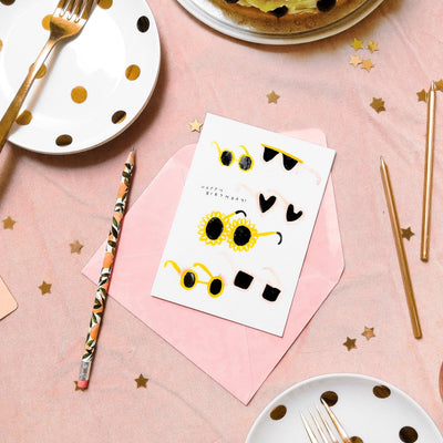 Illustrated Pink And Yellow Sunglasses A6 Card With Pink Envelope On A Table With Gold Stars - Annie Dornan Smith