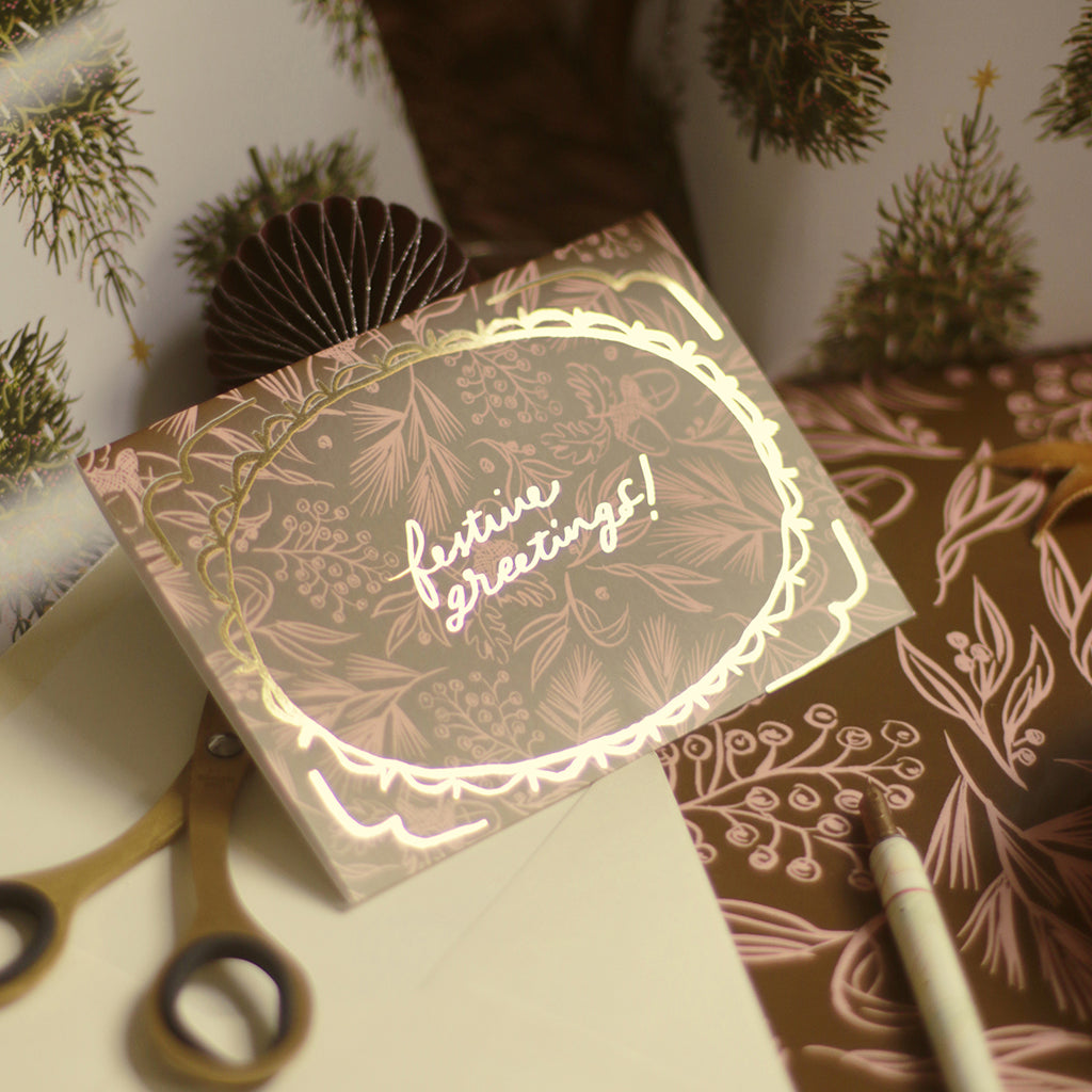 a christmas foliage patterned christmas card. Reads "festive greetings!" in gold foil