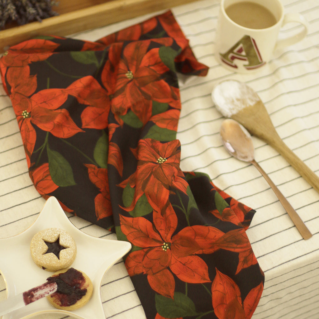 a cotton teatowel with a red poinsettia flower on black design.