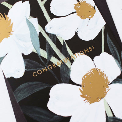 Illustrated White Flowers With Teal Leaves and Gold Centres On A Black Card With Congratulations In Gold With A Black Envelope - Annie Dornan Smith