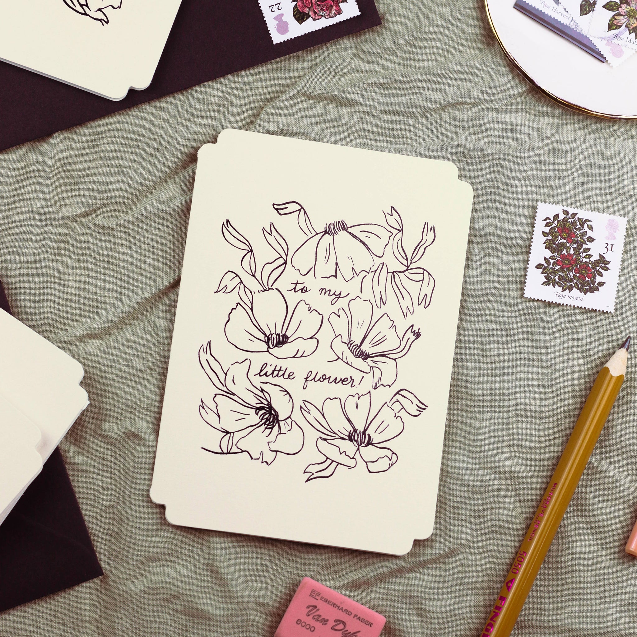 a cream, die-cut card reads "to my little flower", surrounded by linework-style florals, embossed in black foil. Black Line Floral Art Print Love You Beautiful In A Black Frame  - Annie Dornan Smith