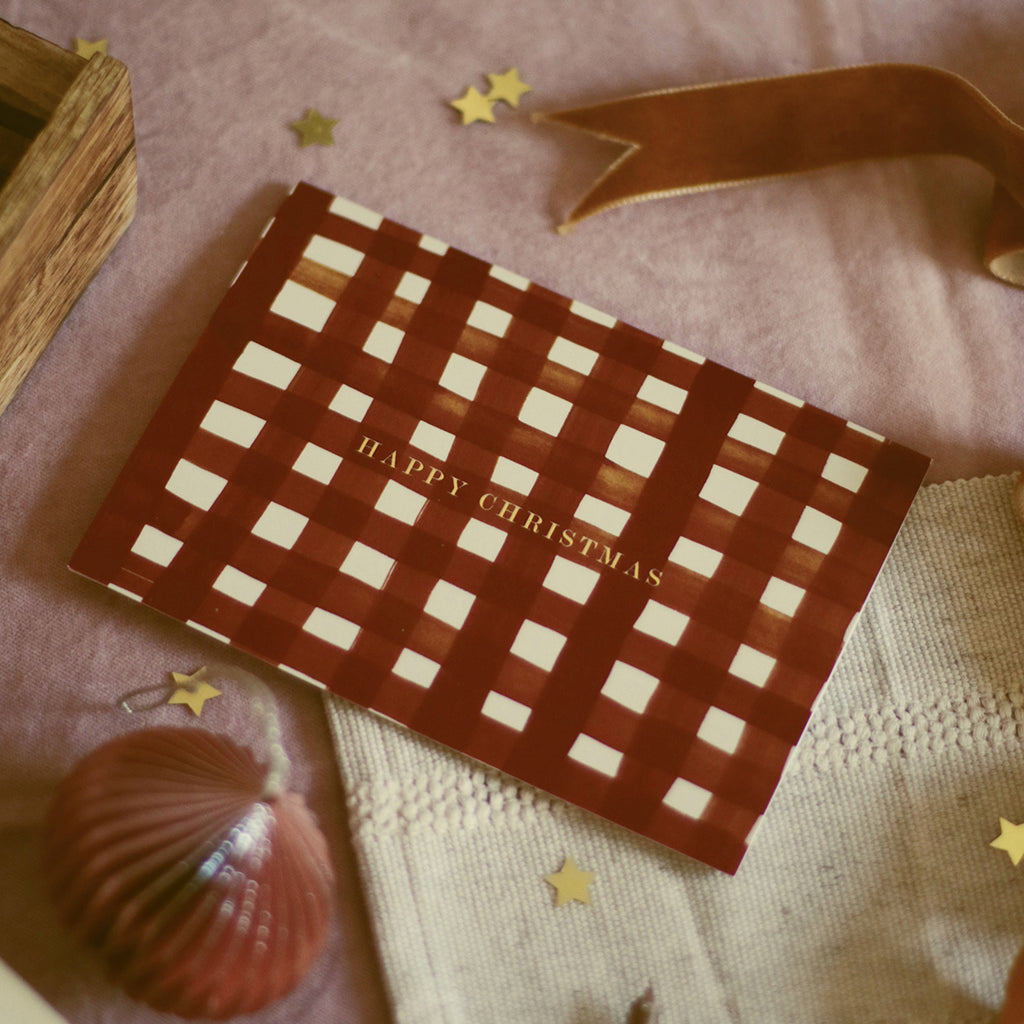 a red gingham patterned christmas card - reads "hapyp christmas" in gold foil