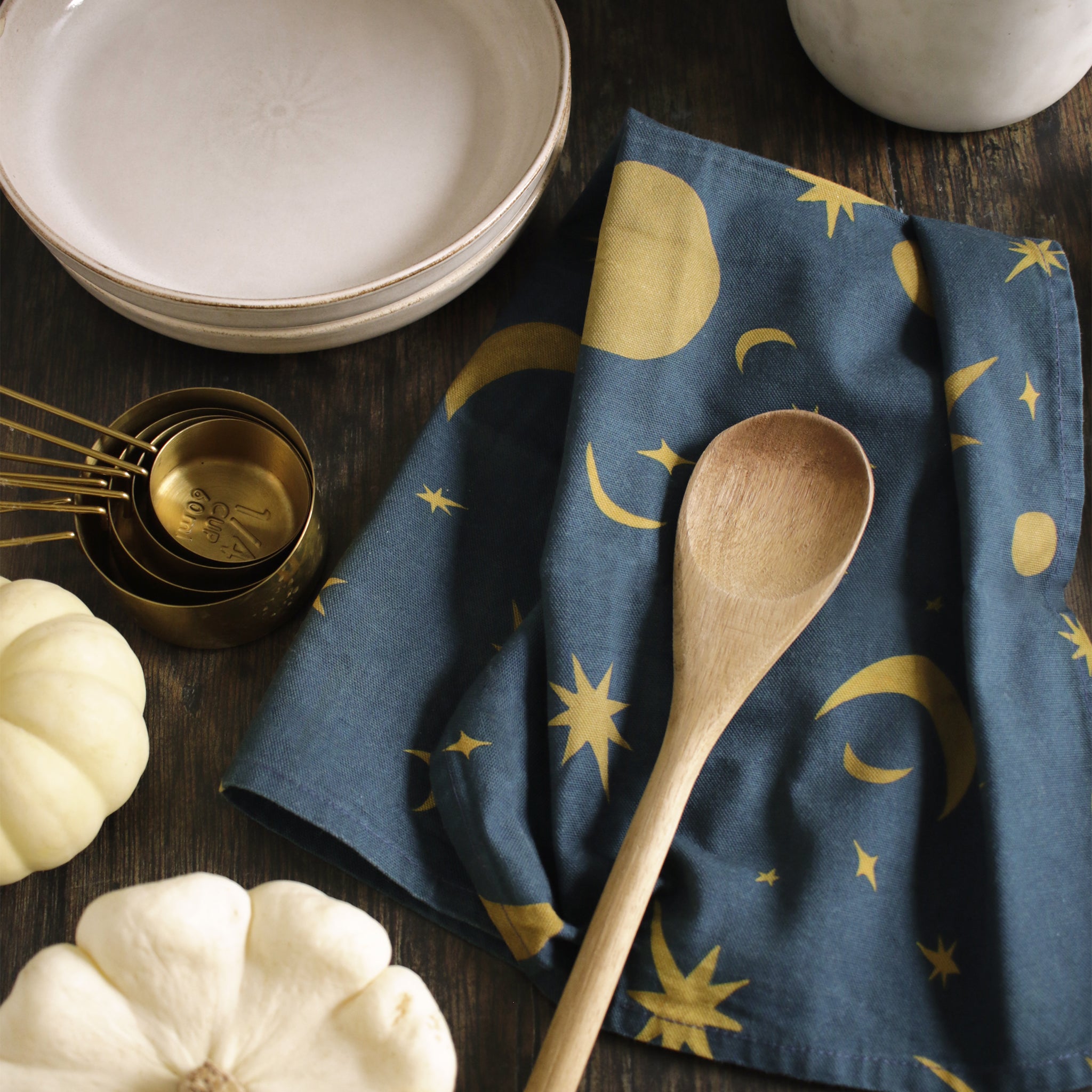 a space-pattern cotton tea towel on a wooden table top, alongside baking ingredients