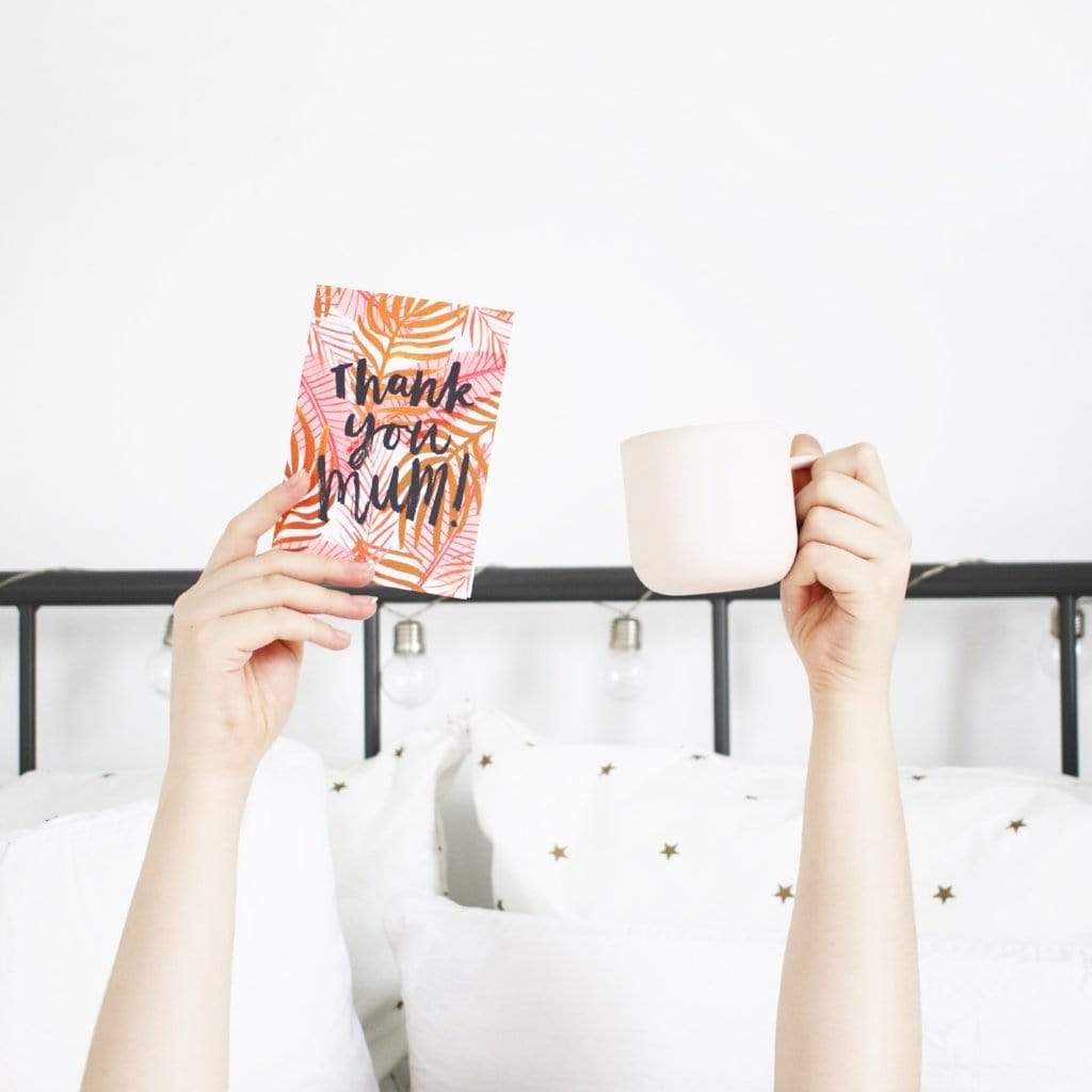 An Illustrated Pink Palm Leaf Card With The Words Thank You Mum Being Held Up With A Cup Of Tea - Annie Dornan Smith