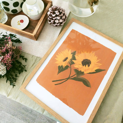 framed painted sunflower print on a green tablecloth