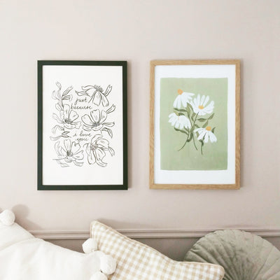 two framed, floral prints hang on a pink wall