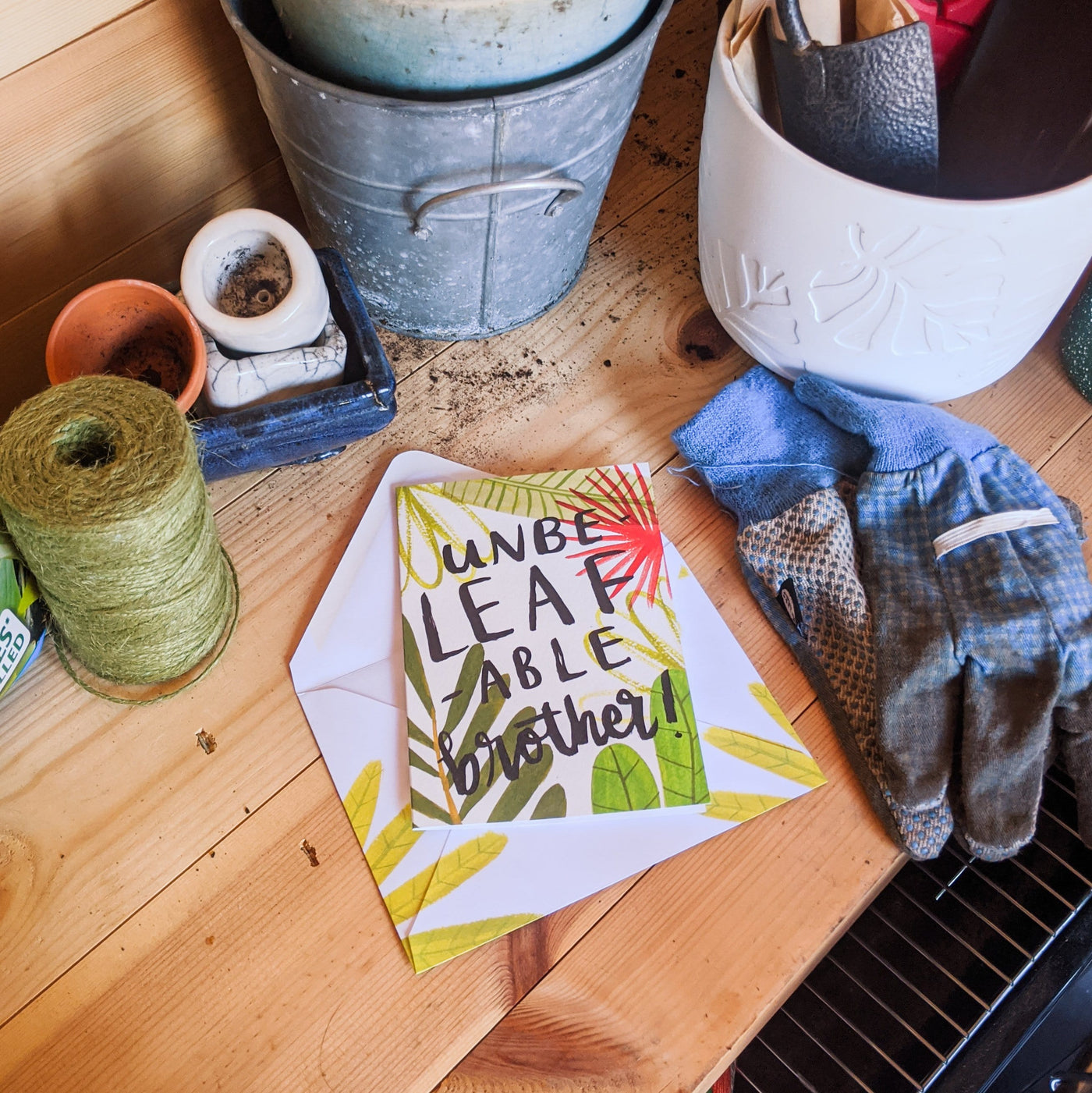 An Illustrated Leaf Greeting Card With The Words Have An Unbeleafable Brother In Brush Lettering On A Potting Bench - Annie Dornan Smith