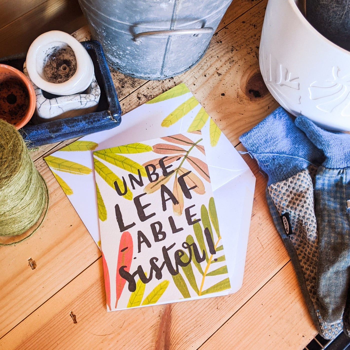 An Illustrated Leaf Greeting Card With The Words Unbeleafable Mum With A Matching Leaf Envelope On A Potting Bench - Annie Dornan Smith