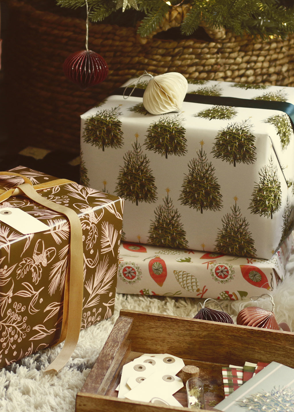 a pile of gifts in illustrated wrapping paper, below the christmas tree