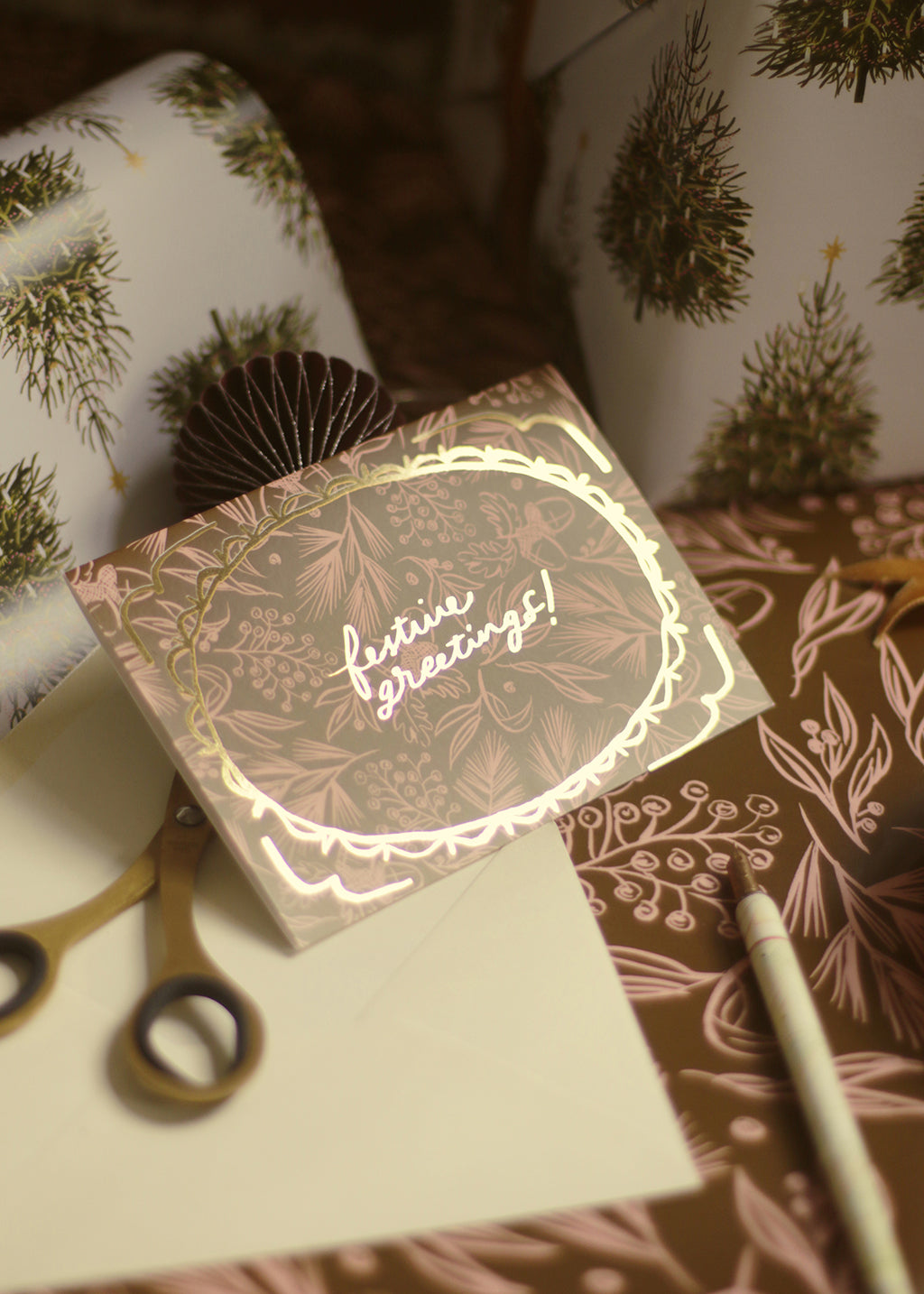 a christmas foliage patterned christmas card. Reads "festive greetings!" in gold foil