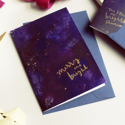 Purple Galaxy Christmas Card With The Words Merry An Bright In Gold With A Deep Navy Envelope - Annie Dornan Smith