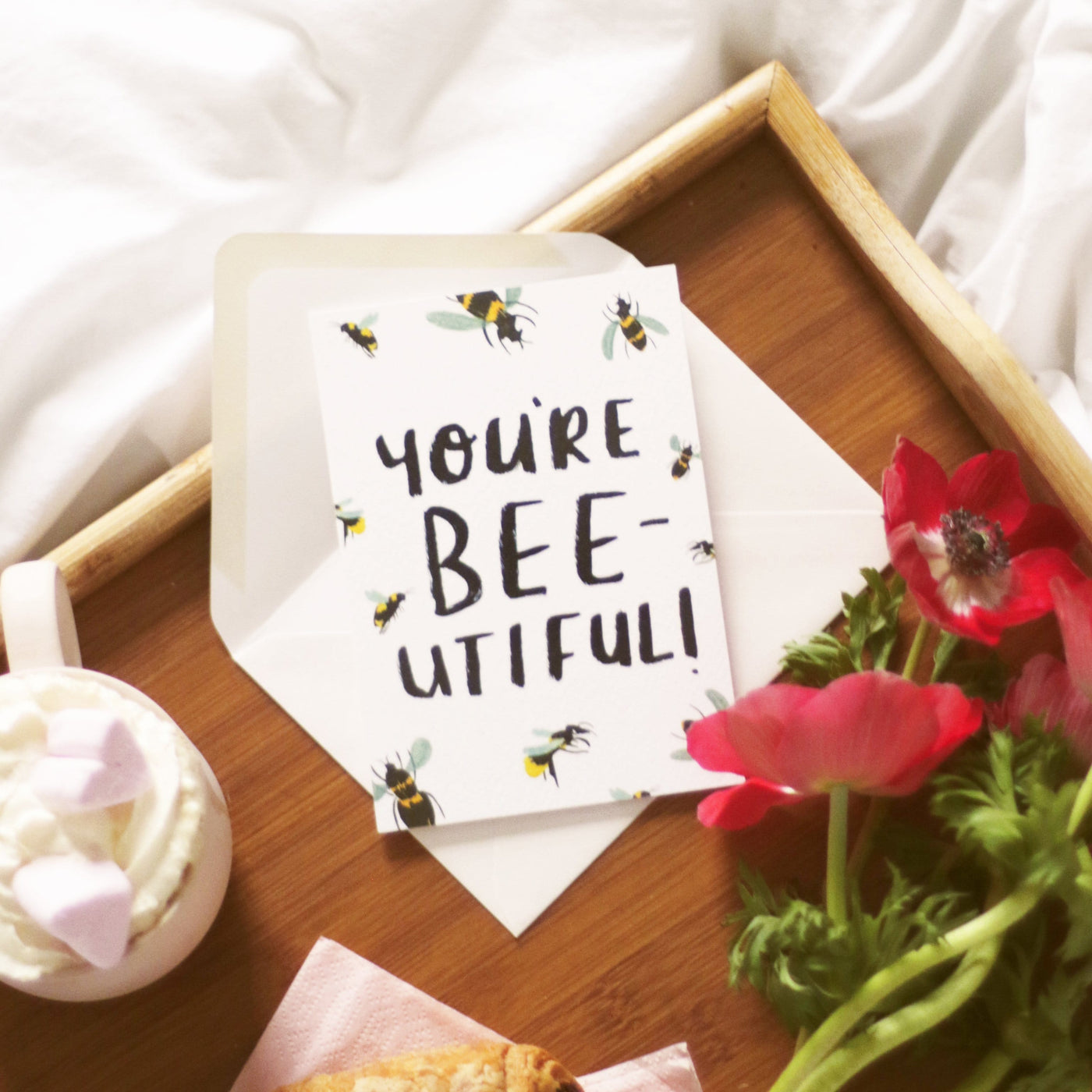 Hand Lettered Greeting Card Reading You're Beeutiful With Illustrated Bees With An Oyster Envelope On A Wooden Tray With A Hot Chocolate And Flowers - Annie Dornan Smith