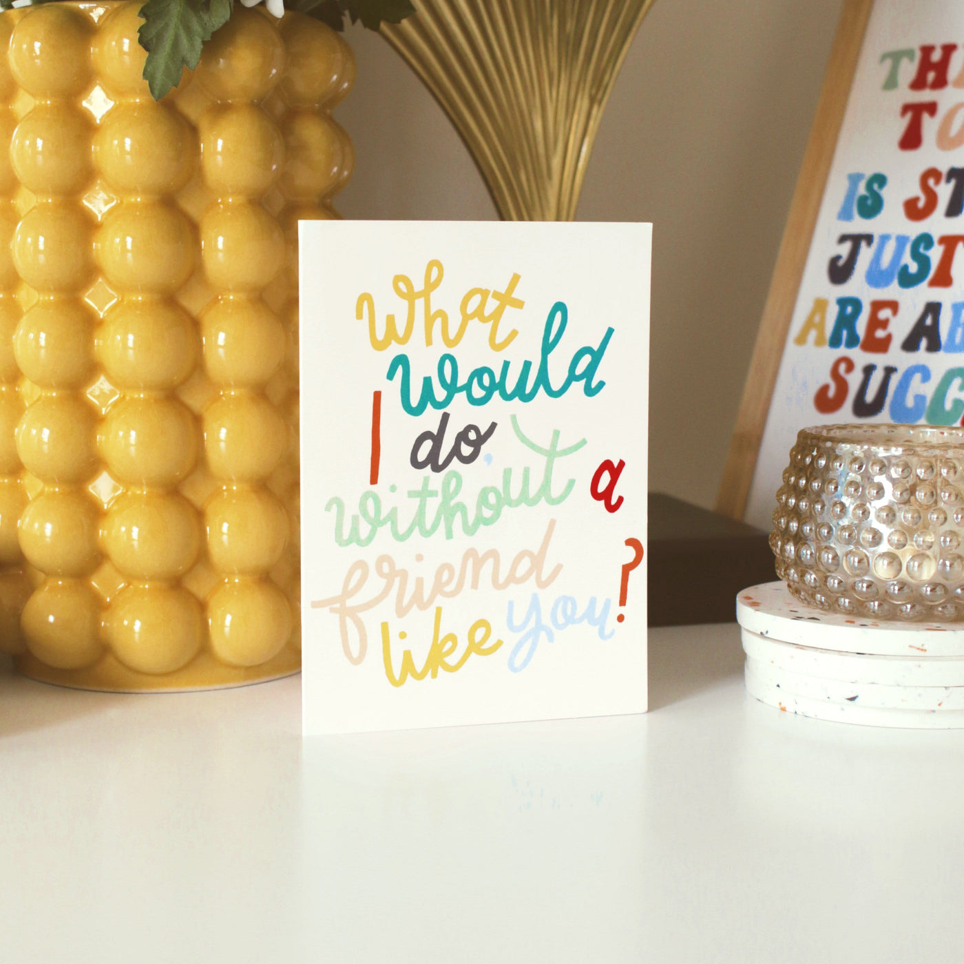A Hand Lettered Rainbow Typography Card Which Reads What Would I Do Without A Friend Like You Next To A Yellow Vase - Annie Dornan Smith