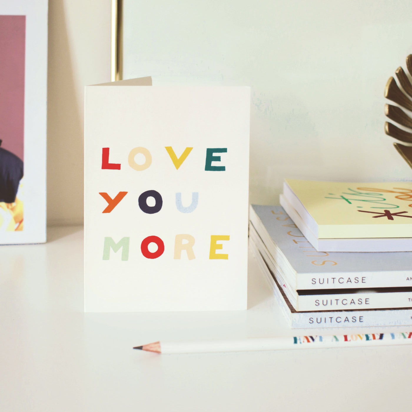 A Hand Lettered Rainbow Typography Card Reading Love You More Next To A Pile Of Books - Annie Dornan Smith