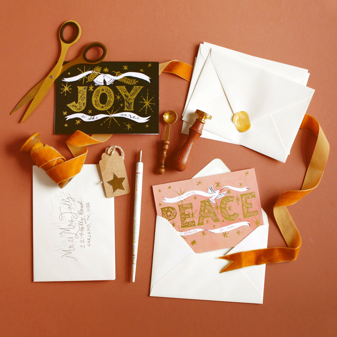 Coral Christmas Card With Gold Peace Lettering And Stars With A White Ribbon And Dove On An Orange Background Orange Velvet Ribbon And Wrapping Accesorries - Annie Dornan Smith