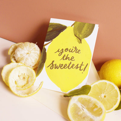 An Illustrated Lemon Card With The Words You're The Sweetest In Gold With A Pale Yellow Envelope With Real Lemons - Annie Dornan Smith