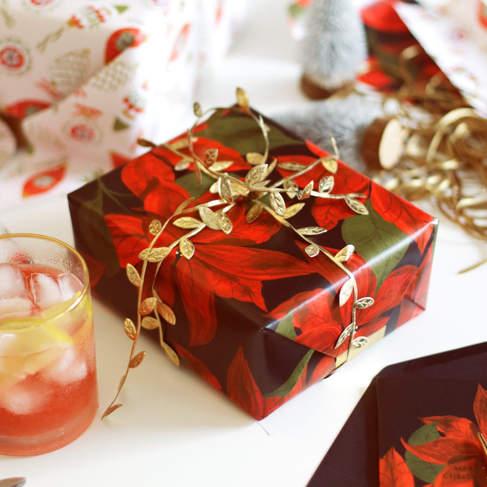 Gift Wrapped In Red Poinsettias Christmas Wrapping Paper With A Gold Leaf Ribbon  - Annie Dornan Smith