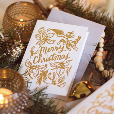 Gold Foiled Mistletoe And Merry Christmas A6 White Car With Grey Envelope Amongst Candles - Annie Dornan Smith