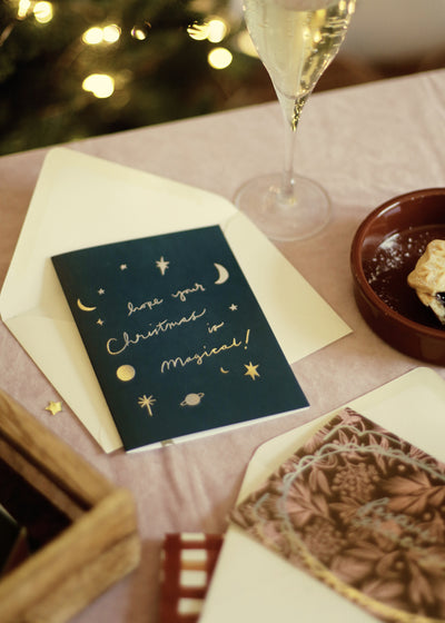 a deep navy christmas card, decorated with gold foiled moons and stars