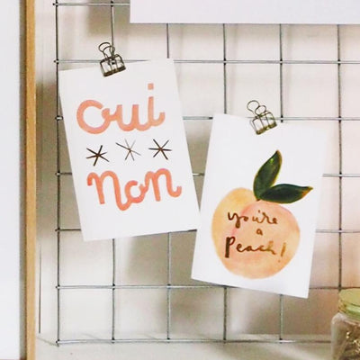 Typographic A6 Card With The Words Oui Non And Three Stars In Pink With You're A Peach Card Clipped On A Noticeboard - Annie Dornan Smith