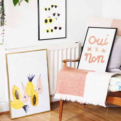 Typographic Print With The Words Oui Non And Three Stars In Peach In A Black Frame Leaning On A Chair - Annie Dornan Smith