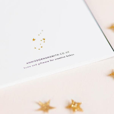 The Back Of A Christmas Card With Web Address and Small Gold Stars - Annie Dornan Smith