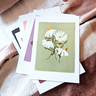 A Botanical Green With White Cone Flowers Floral Print On A Pile Of Other Spring Prints - Annie Dornan Smith