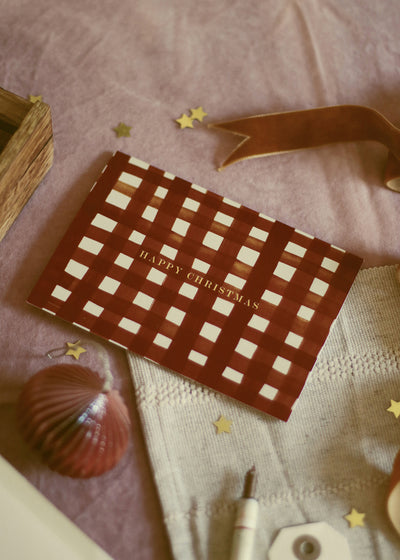a red gingham patterned christmas card - reads "hapyp christmas" in gold foil