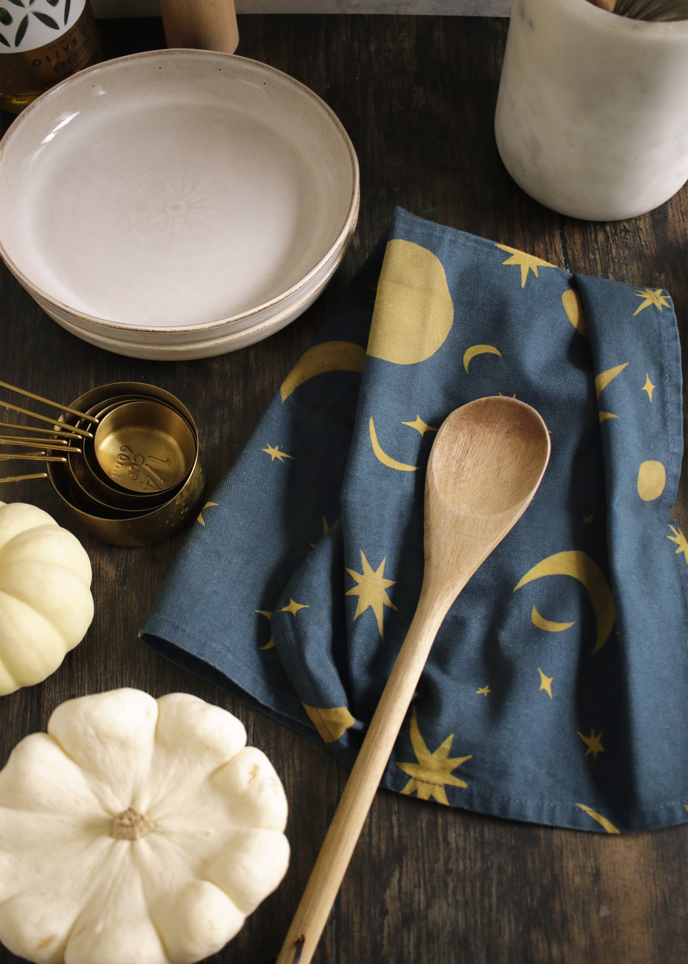 a space-pattern cotton tea towel on a wooden table top, alongside baking ingredients