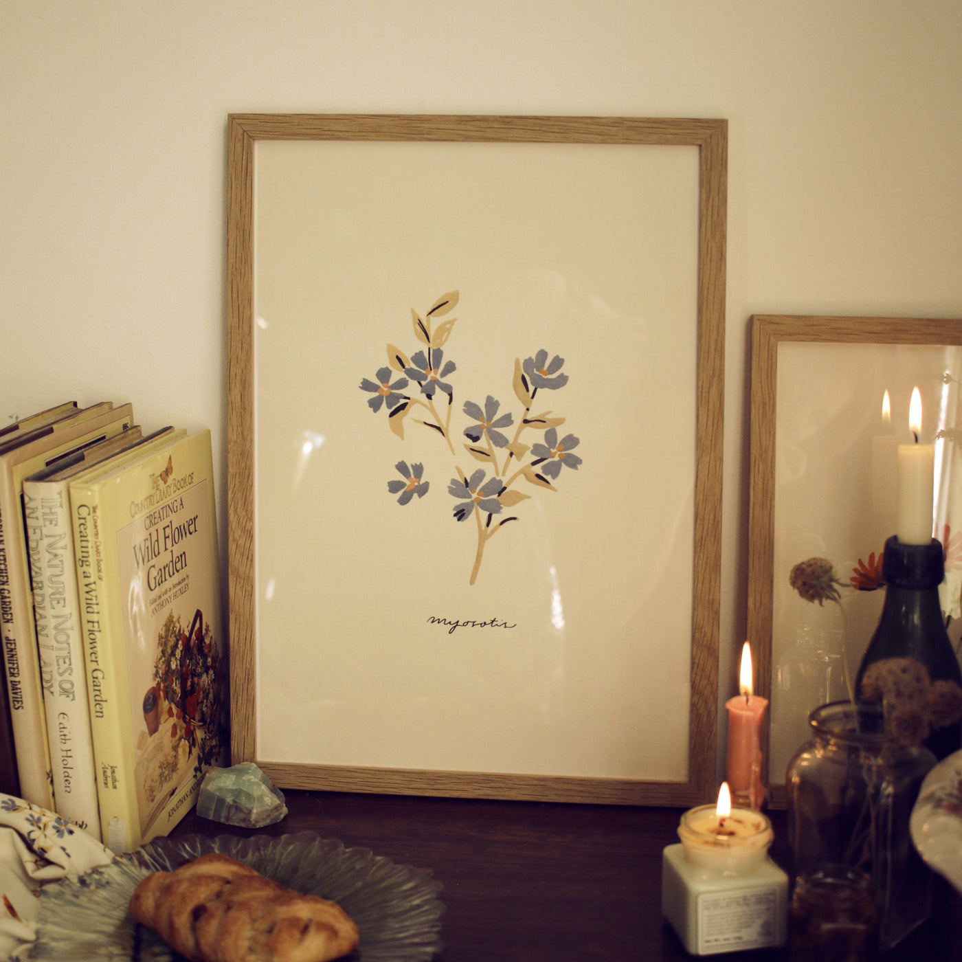 forget me not print framed in oak frame on a table decorated with books and candles