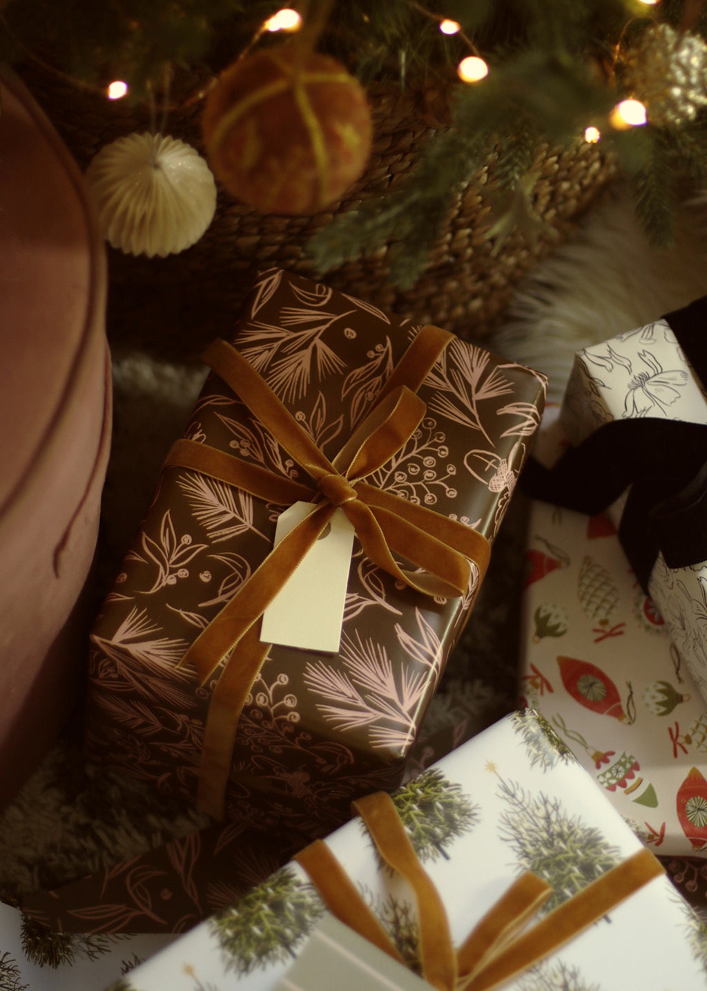 a gift wrapped in brown foliage patterned wrapping paper sits under the tree