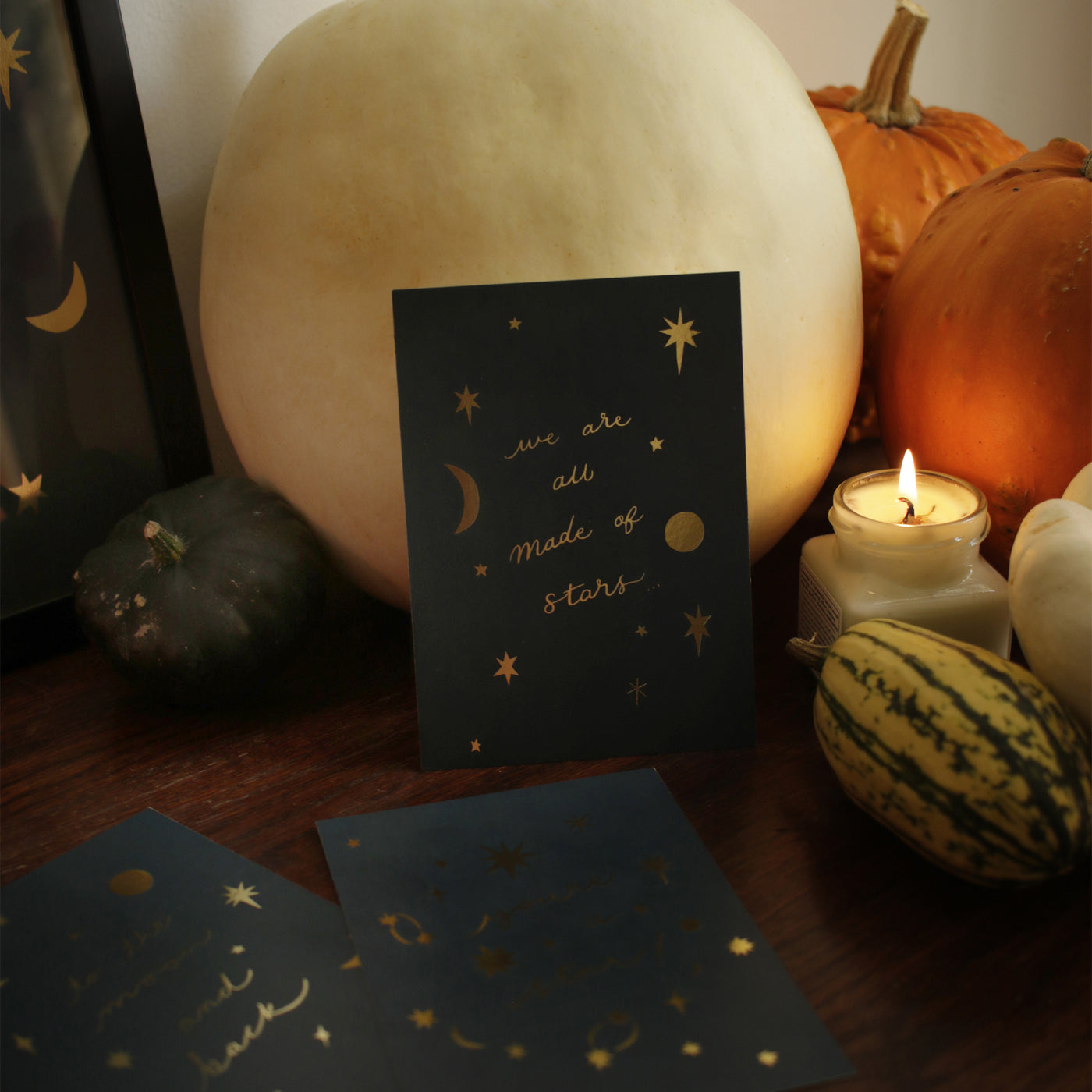 made of stars gold foil postcard surrounded by autumnal pumpkins and candles