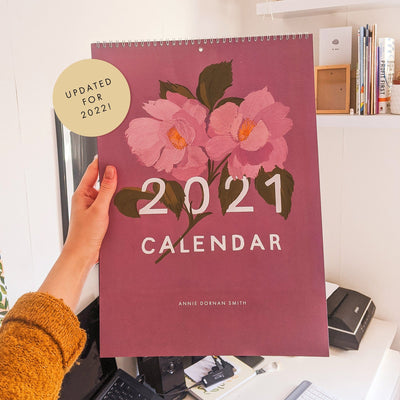holding last year's 2021 calendar in my studio. A label on the image says "updated for 2022!".